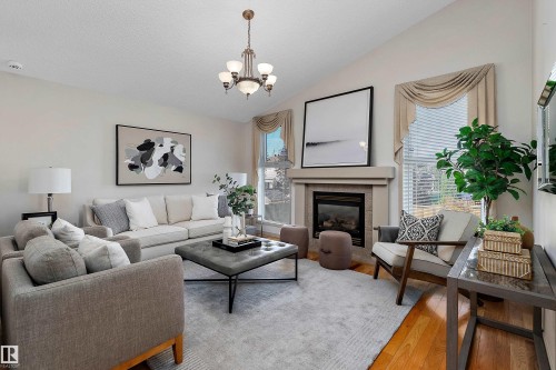 Vaulted ceiling, gas fireplace with tile surround, hardwood flooring, large windows, and a chandelier - 1046 Blackburn Close Sw, Edmonton, AB 
