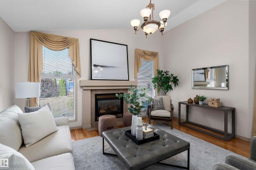 Vaulted ceiling, recessed fireplace with hearth, chandelier lighting, and wood-finish flooring - 1046 Blackburn Close Sw, Edmonton, AB 
