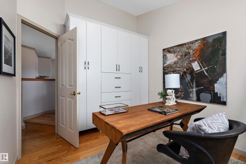 Integrated white cabinetry with drawers, wood-finish flooring, and a solid wood desk - 1046 Blackburn Close Sw, Edmonton, AB 