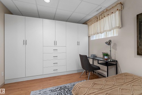Built-in white cabinetry with chrome hardware, integrated drawers, and wood-finish flooring - 1046 Blackburn Close Sw, Edmonton, AB 