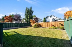 Expansive backyard featuring a manicured lawn, a blend of green and natural wood fencing, and established perimeter landscaping - 