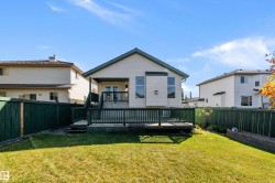 Expansive lawn with perimeter fencing, leading to a multi-level deck and covered patio - 