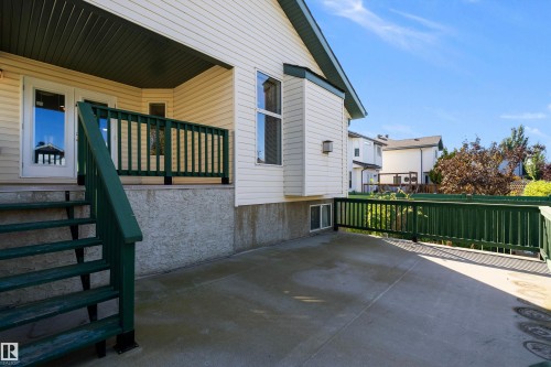 Expansive concrete patio with painted wood railing, direct access via exterior stairs, and a siding exterior - 1046 Blackburn Close Sw, Edmonton, AB 