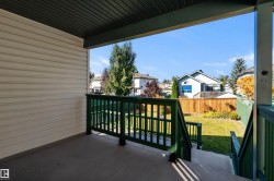 Covered outdoor balcony with green painted railings, concrete flooring, and a privacy wall - 