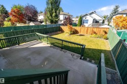 Expansive concrete patio with green wood railings, leading to a manicured lawn area - 