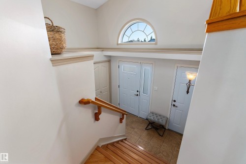 Vaulted ceiling with an arched transom window, wood-finish staircase, and tile flooring at the entry - 1046 Blackburn Close Sw, Edmonton, AB 