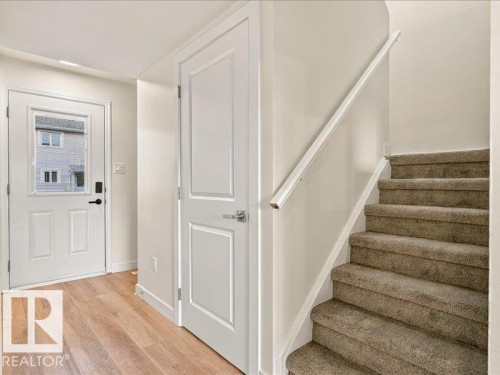 Wood-finish flooring, white paneled door, carpeted staircase, and a white handrail - 18325 66 Avenue Nw, Edmonton, AB 