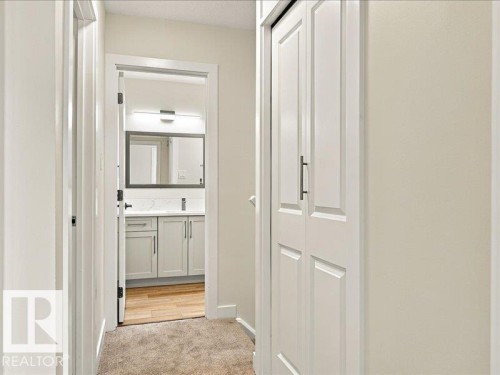 Hallway featuring carpeted flooring and white paneled doors - 18325 66 Avenue Nw, Edmonton, AB 