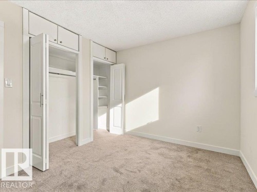 Wall-to-wall carpeting with built-in closets featuring bi-fold doors, hanging rods, and overhead cabinetry - 18325 66 Avenue Nw, Edmonton, AB 