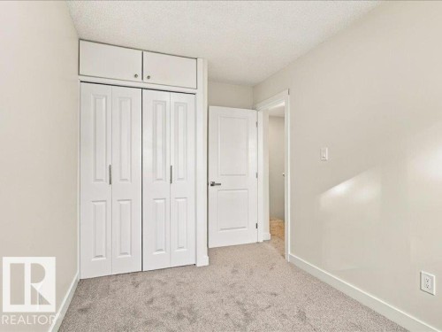 Wall-to-wall carpeting, bi-fold closet doors, integrated upper cabinetry, and a white interior door - 18325 66 Avenue Nw, Edmonton, AB 