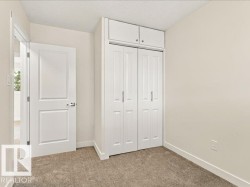 Neutral-toned carpeting, white bi-fold closet doors, integrated upper cabinetry, and a solid interior door - 