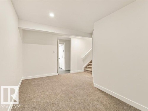 Recessed ceiling lighting, neutral carpet flooring, white painted walls, white trim, and a staircase with carpeted treads - 18325 66 Avenue Nw, Edmonton, AB 