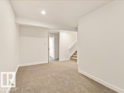 Recessed ceiling lighting, neutral carpet flooring, white painted walls, white trim, and a staircase with carpeted treads - 