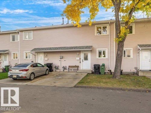 Siding exterior with multiple double-pane windows, a paved driveway, and established landscaping - 18325 66 Avenue Nw, Edmonton, AB 