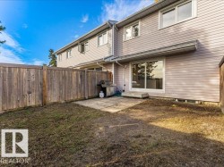 Enclosed backyard with a wood privacy fence, concrete patio, and sliding glass door access - 