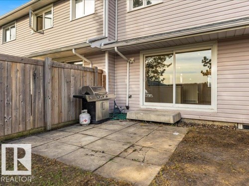 Patio area featuring concrete pavers, wood fencing, and a large sliding glass door - 18325 66 Avenue Nw, Edmonton, AB 