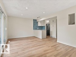 Wood-finish flooring, recessed lighting, sliding glass door, kitchen with light cabinetry, and blue tiled backsplash - 