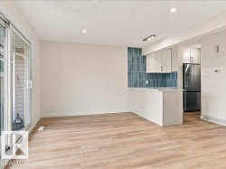 Sliding glass doors, wood-finish flooring, recessed lighting, white cabinetry, and a blue tile backsplash - 