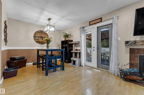 Wood-finish flooring, two-tone wall treatment with chair rail, built-in shelving, fireplace with tile surround and wood mantel, and double glass-panel doors - 1920 145 Avenue Nw, Edmonton, AB 