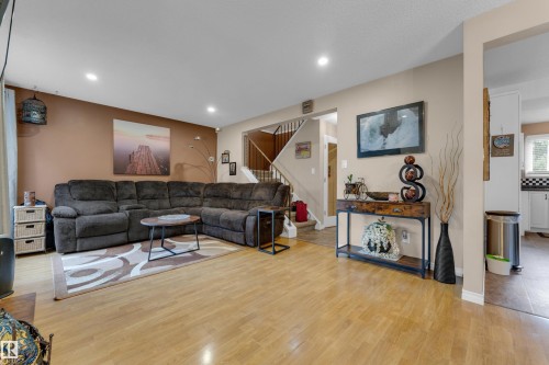 Wood-finish flooring throughout, recessed ceiling lighting, and a staircase with a white railing - 1920 145 Avenue Nw, Edmonton, AB 