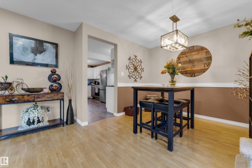 Wood-finish flooring throughout, two-tone painted walls with chair rail molding, and a square open-frame chandelier - 1920 145 Avenue Nw, Edmonton, AB 