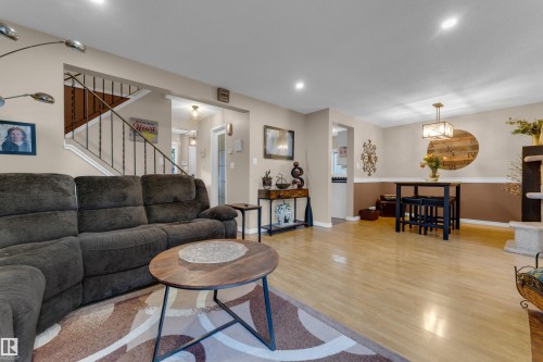 Open-concept living space featuring wood-finish flooring, recessed lighting, and a wrought iron staircase - 1920 145 Avenue Nw, Edmonton, AB 