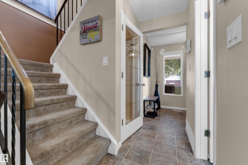 Carpeted staircase with wrought iron railing and leading to an upper level - 1920 145 Avenue Nw, Edmonton, AB 