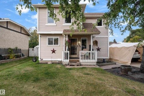 Two-story home with vinyl siding exterior, front porch with white railing and mature landscaping - 1920 145 Avenue Nw, Edmonton, AB 