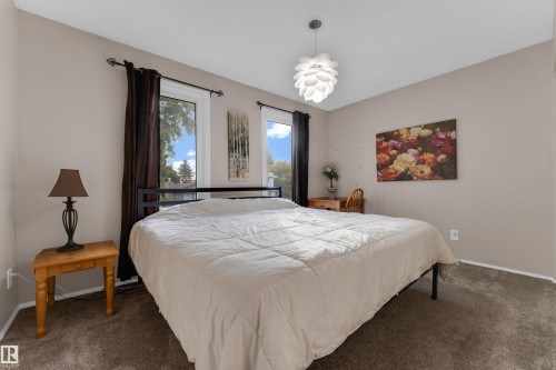 Neutral-toned walls, two windows with dark drapery, and a contemporary pendant light fixture - 1920 145 Avenue Nw, Edmonton, AB 