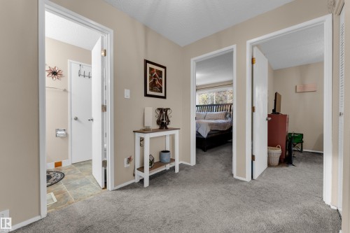 Neutral-toned walls complement the gray carpeting throughout, with a bathroom featuring multi-toned tile flooring and a bedroom with large windows - 1920 145 Avenue Nw, Edmonton, AB 