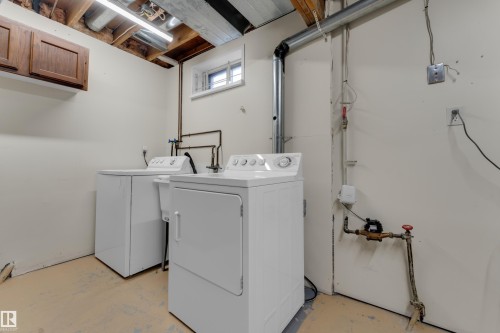 Laundry area featuring exposed ceiling joists, overhead fluorescent lighting, a window with security bars, and an upper wood-finish cabinet - 1920 145 Avenue Nw, Edmonton, AB 