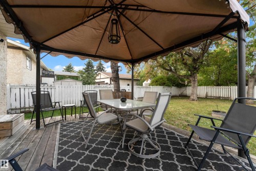 Expansive backyard with a wooden deck, covered gazebo, and white picket fencing - 1920 145 Avenue Nw, Edmonton, AB 