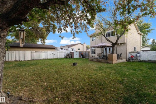 Expansive backyard featuring a large green space, a full privacy fence, and a wooden deck - 1920 145 Avenue Nw, Edmonton, AB 