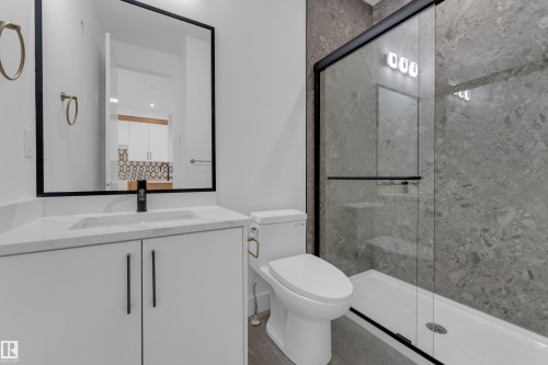 White vanity with a single basin, black framed mirror, and matte black faucet - 512 Robinson Boulevard, Leduc, AB 