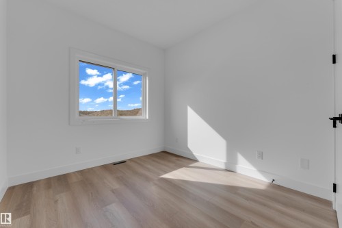 Wood-finish flooring with white wall finishes, a white window frame, and a black door handle - 512 Robinson Boulevard, Leduc, AB 