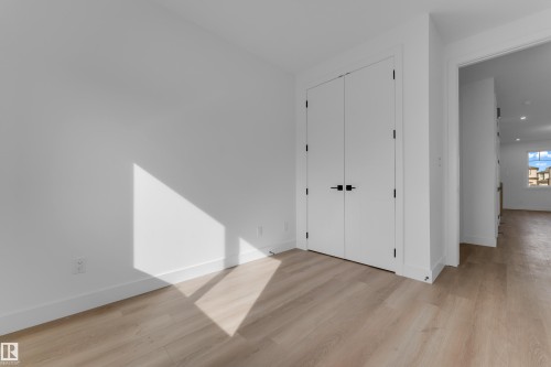 Light wood-finish flooring, white walls, and a closet with double doors featuring matte black hardware - 512 Robinson Boulevard, Leduc, AB 