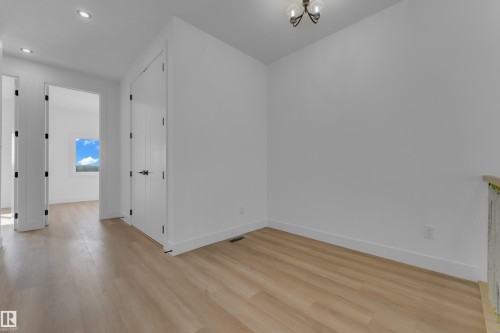 Recessed lighting, wood-finish flooring, white walls, white doors with black hardware, and a bronze chandelier - 512 Robinson Boulevard, Leduc, AB 