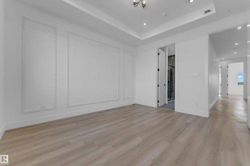 Recessed lighting, wood-finish flooring, tray ceiling, decorative wall molding, and interior doorway leading to a bathroom with a glass-enclosed shower - 512 Robinson Boulevard, Leduc, AB 