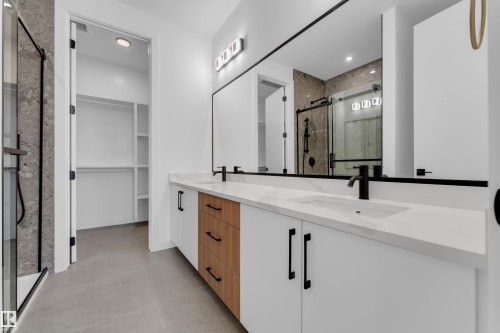 Dual vanity with a white countertop and integrated sinks, matte black fixtures, and a large wall-mounted mirror - 512 Robinson Boulevard, Leduc, AB 