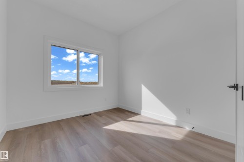 Wood-finish flooring, white painted walls, white trim, and a window with white casing - 512 Robinson Boulevard, Leduc, AB 