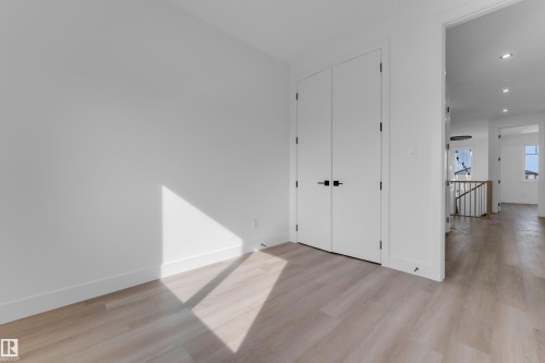 Wood-finish flooring throughout, bright white walls, double panel doors with matte black hardware, and recessed lighting - 512 Robinson Boulevard, Leduc, AB 