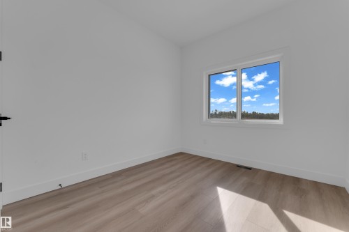 Neutral wall paint, wood-finish flooring, white trim, and a window with a natural backdrop - 512 Robinson Boulevard, Leduc, AB 
