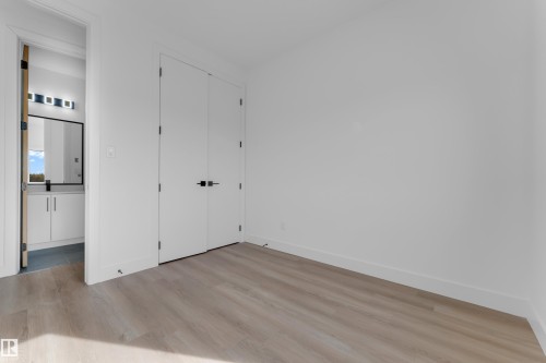 Light wood-finish flooring, white walls, and a double-door closet with matte black hardware - 512 Robinson Boulevard, Leduc, AB 