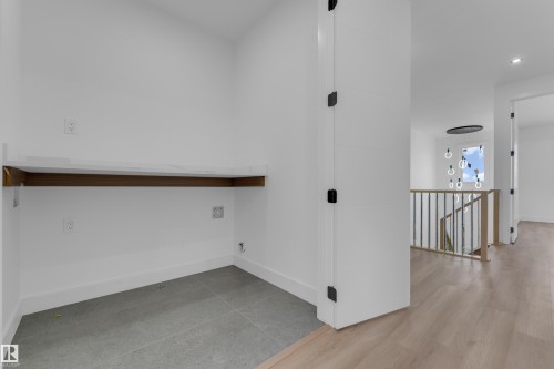 Laundry alcove with a built-in counter, tile flooring, and wood-finish flooring in the hallway - 512 Robinson Boulevard, Leduc, AB 
