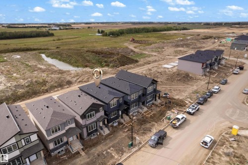 Newly constructed townhomes with dark shingle roofing, light-toned siding, and visible construction progress - 512 Robinson Boulevard, Leduc, AB 