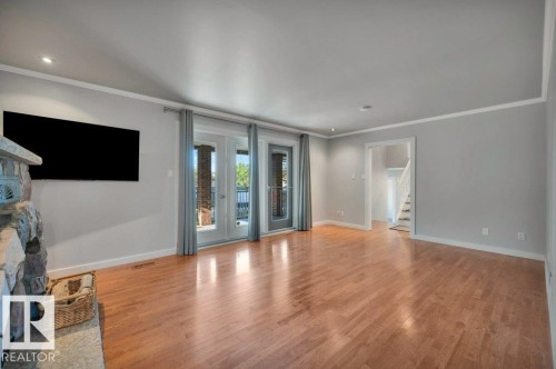 Hardwood floors, large patio doors and stone fireplace. Wall mounted TV (included). - 895 Lee Ridge Road Nw, Edmonton, AB 