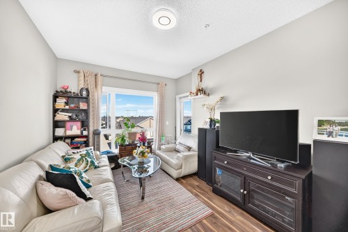 Wood-finish flooring, built-in shelving, and a glass-paneled sliding door - #404 12804 140 Av Nw, Edmonton, AB 