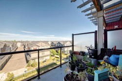 Balcony with frosted glass privacy panels, black metal railing, and a wooden pergola structure - 