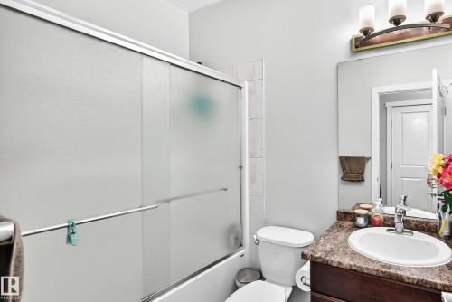 Frosted glass shower enclosure, integrated shower-over-tub, tile surround, vanity with an integrated sink, and a framed mirror - #404 12804 140 Av Nw, Edmonton, AB 