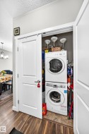 Laundry closet featuring a stackable washer and dryer, wood-finish flooring, white doors, and brushed nickel hardware - 